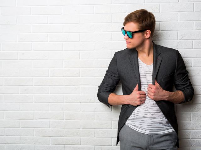 portrait-smiling-stylish-man-sunglasses-standing-against-brick-wall-modern-office